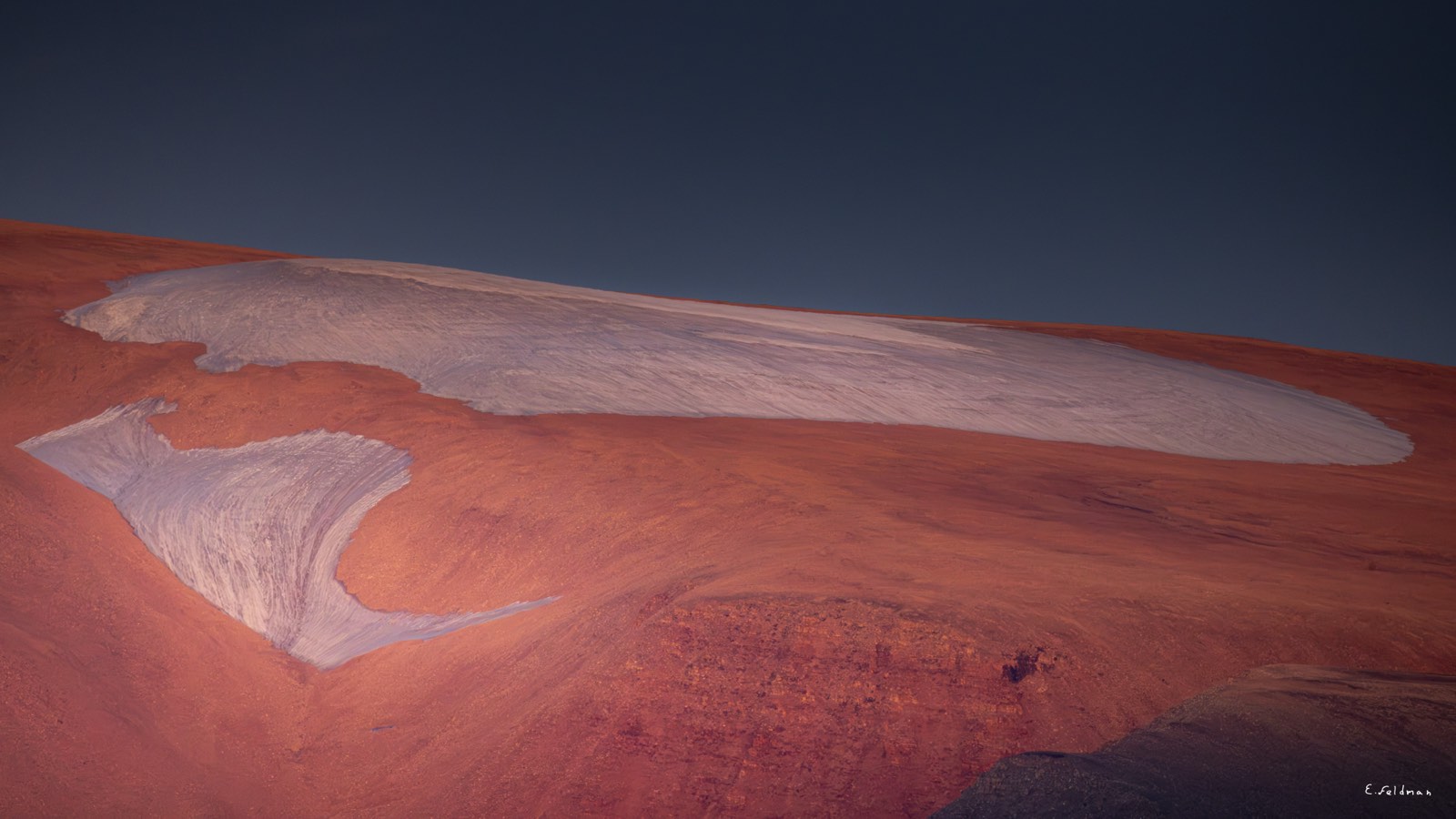 Snow patterns on a red mountainside